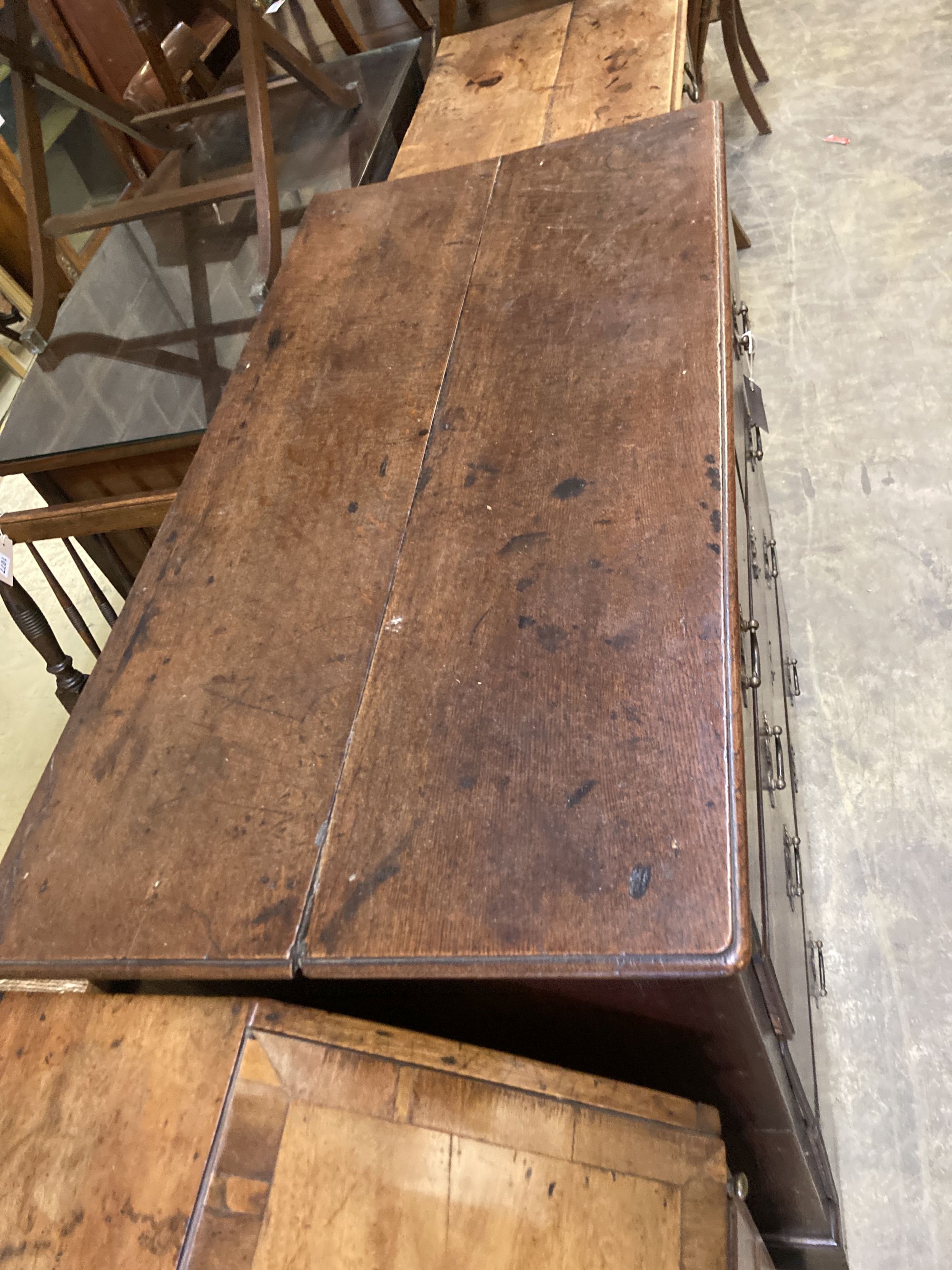 A George II provincial oak chest of two short and three long drawers, with brass drop handles and ogee arched frieze, on bracket feet,